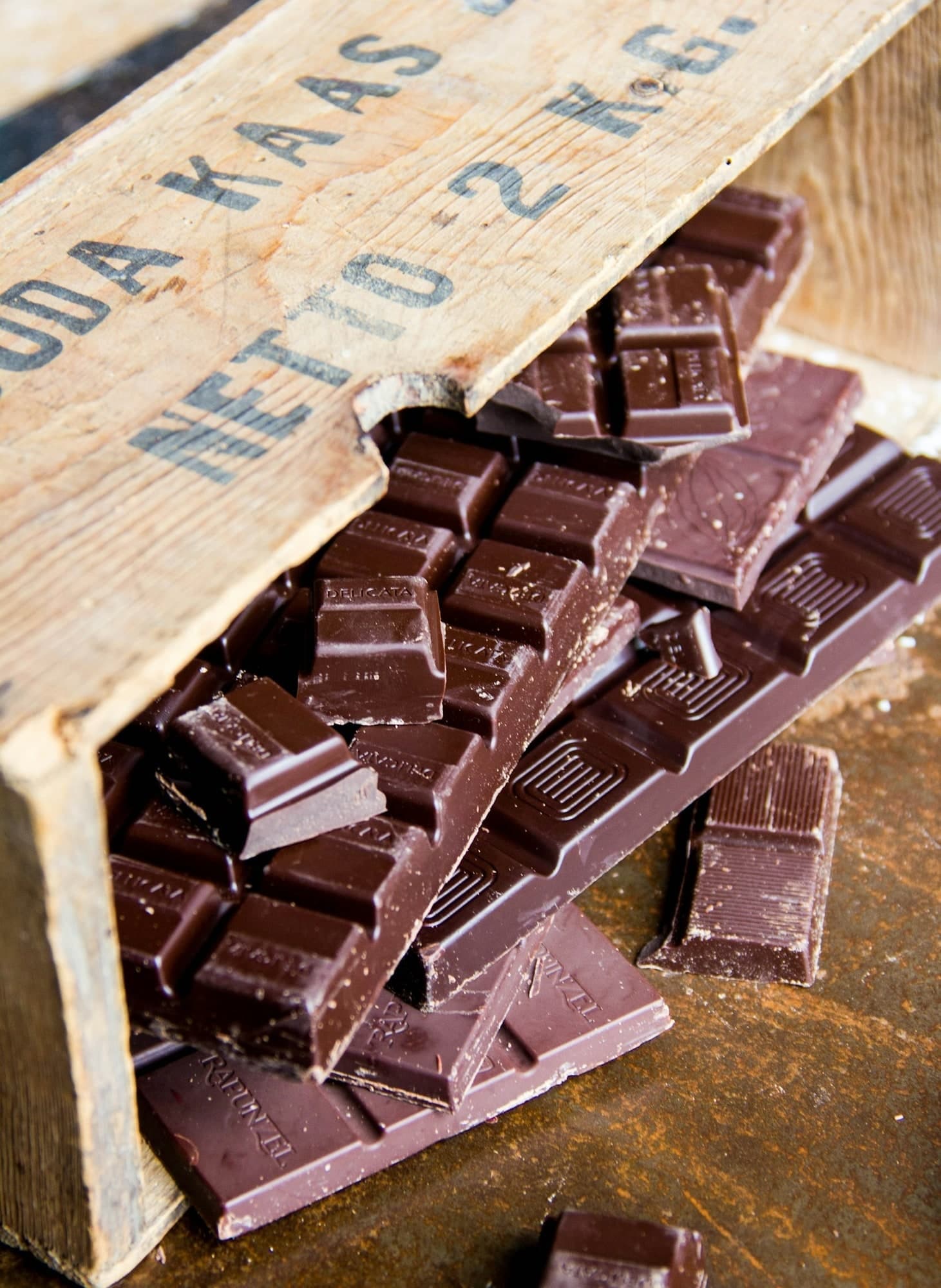 Dark chocolate bars and pieces arranged in a rustic wooden crate